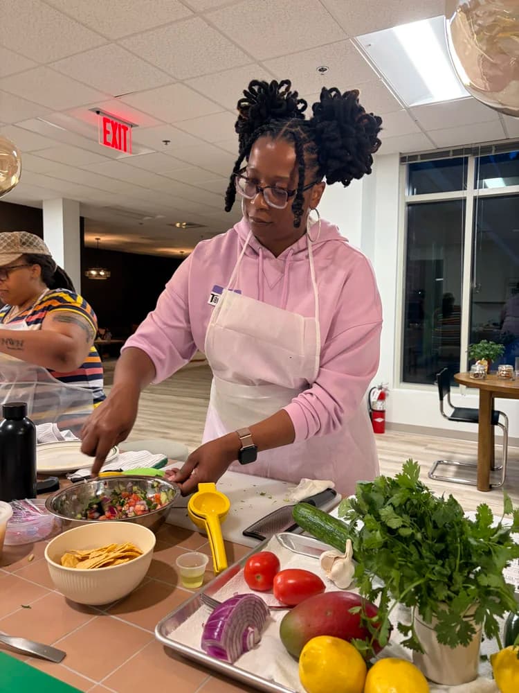 An adult participant prepares fresh ingredients during a Kind Kitchen class