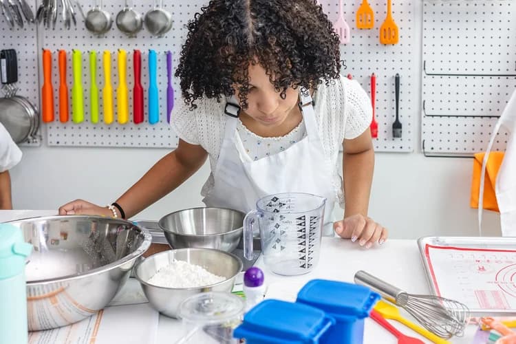 A young cook studies measurements beside bowls and kitchen tools