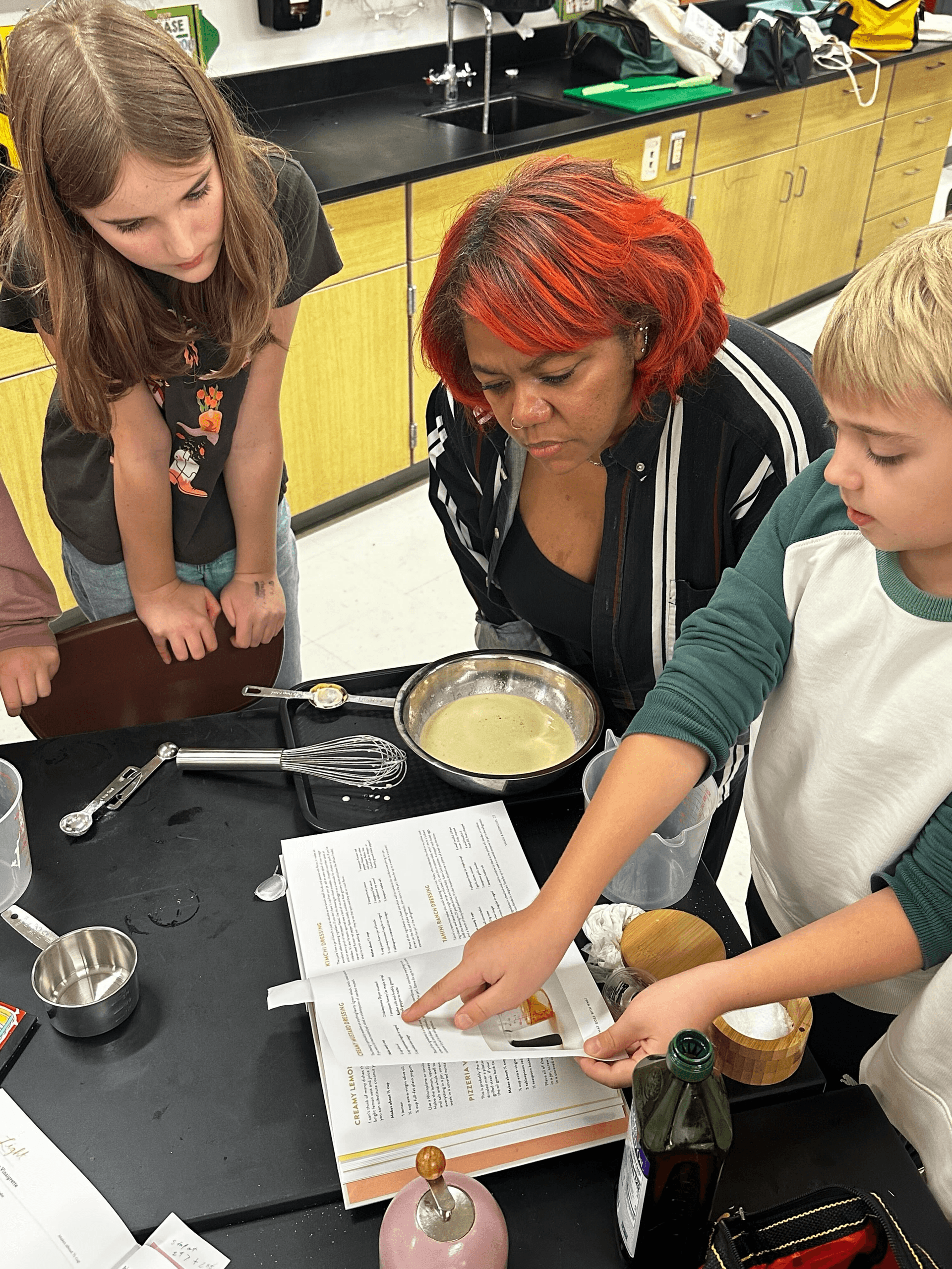 A young cook studies measurements beside bowls and kitchen tools